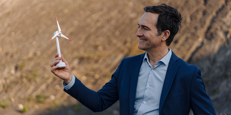 man holding a white wind turbine model in his hand