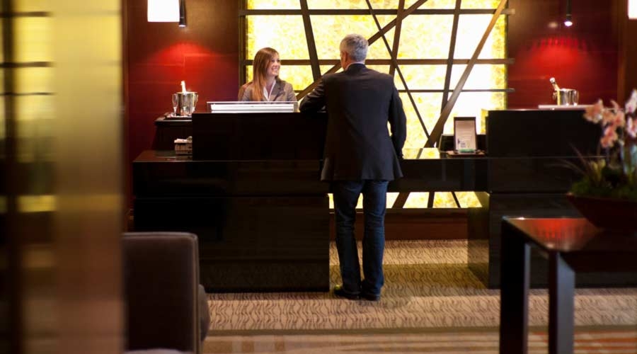 Businessmen speaking with staff at the front desk reception of a luxury hotel