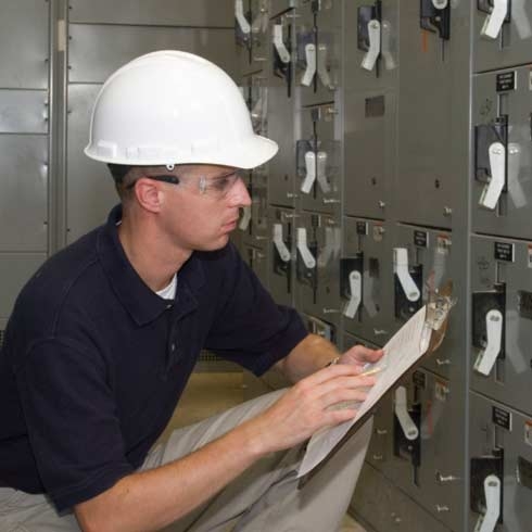 A technician checking on the electrical machine and recording notes, electricity generation, electrical energy, data management.
