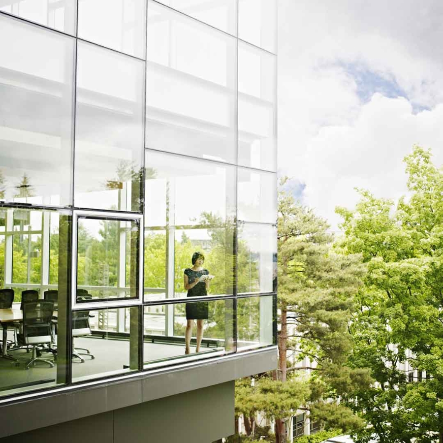 Lady standing near the glass window at a office