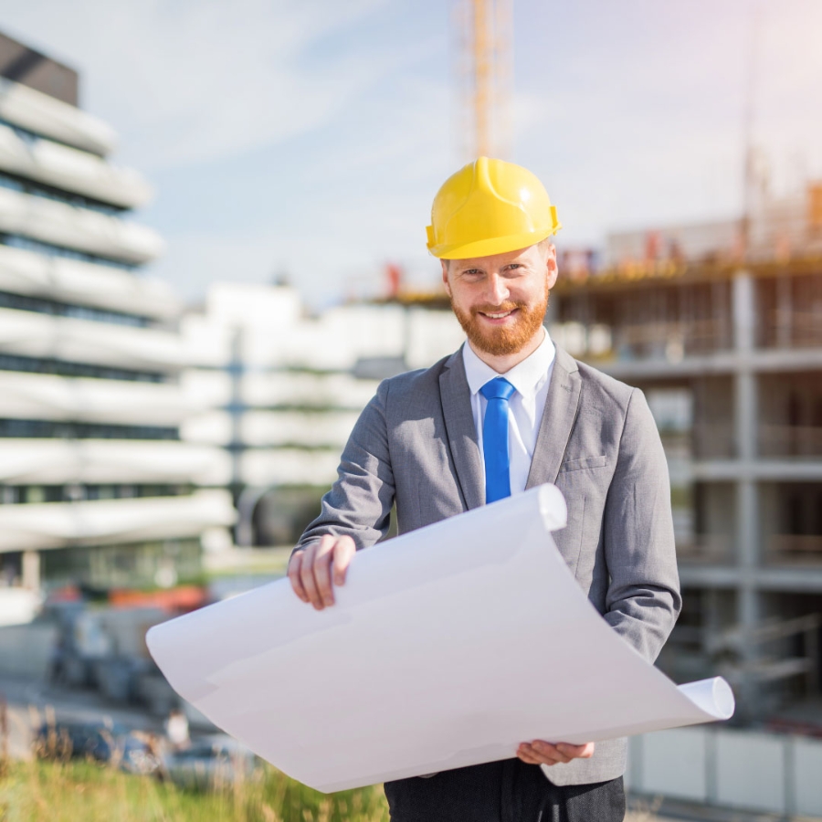 A man wearing hard hat at a construction holding a site design sheet in his hand