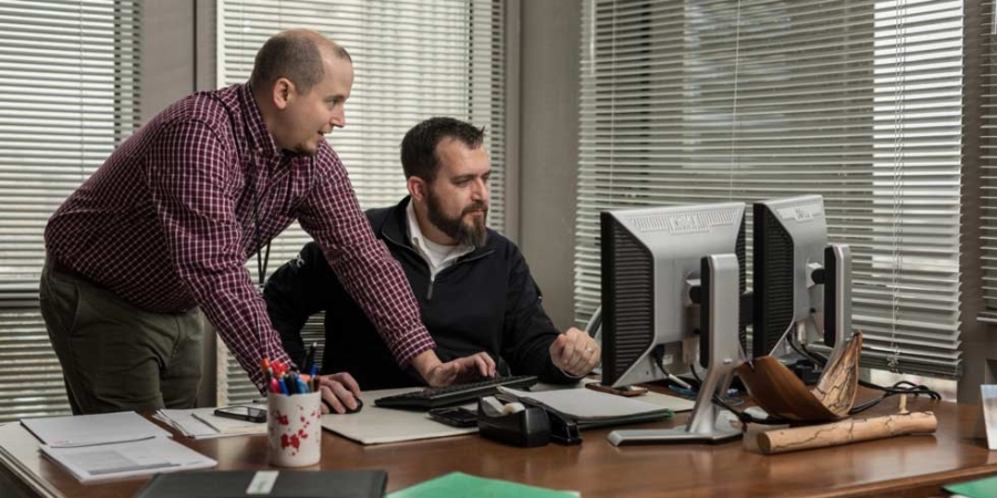 επιχειρηματίες στο γωνιακό γραφείο κοιτάζουν στις οθόνες των υπολογιστών στα Συνταξιοδοτικά συστήματα της Αλαμπάμα