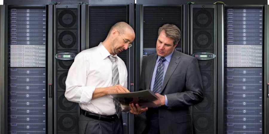 Two mature man checking computers in server room