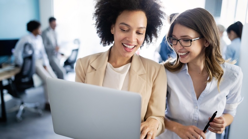 Two woman smiling in office while working