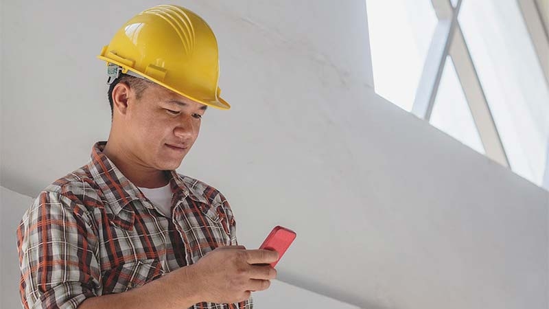 A person wearing a hard hat and looking at his phone