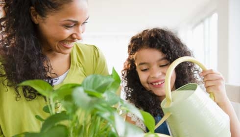 Mother and daughter watering plant together