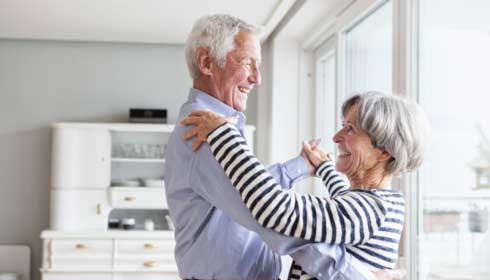 Senior couple dancing together at home at home