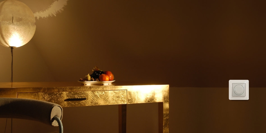Living room in golden lights with fruits on a desk and with connected white switch on the wall