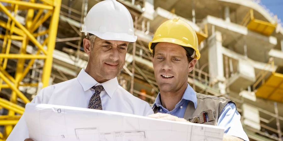 Two men looking at blueprints together at a construction site