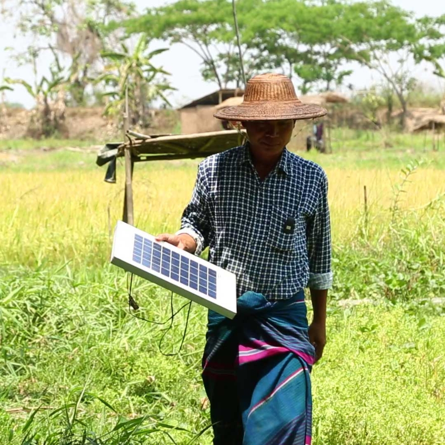 A person in a straw hat holding a solar panel