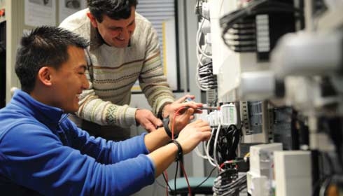 A worker showing a coworker how to use a multimeter, asset management, energy efficiency