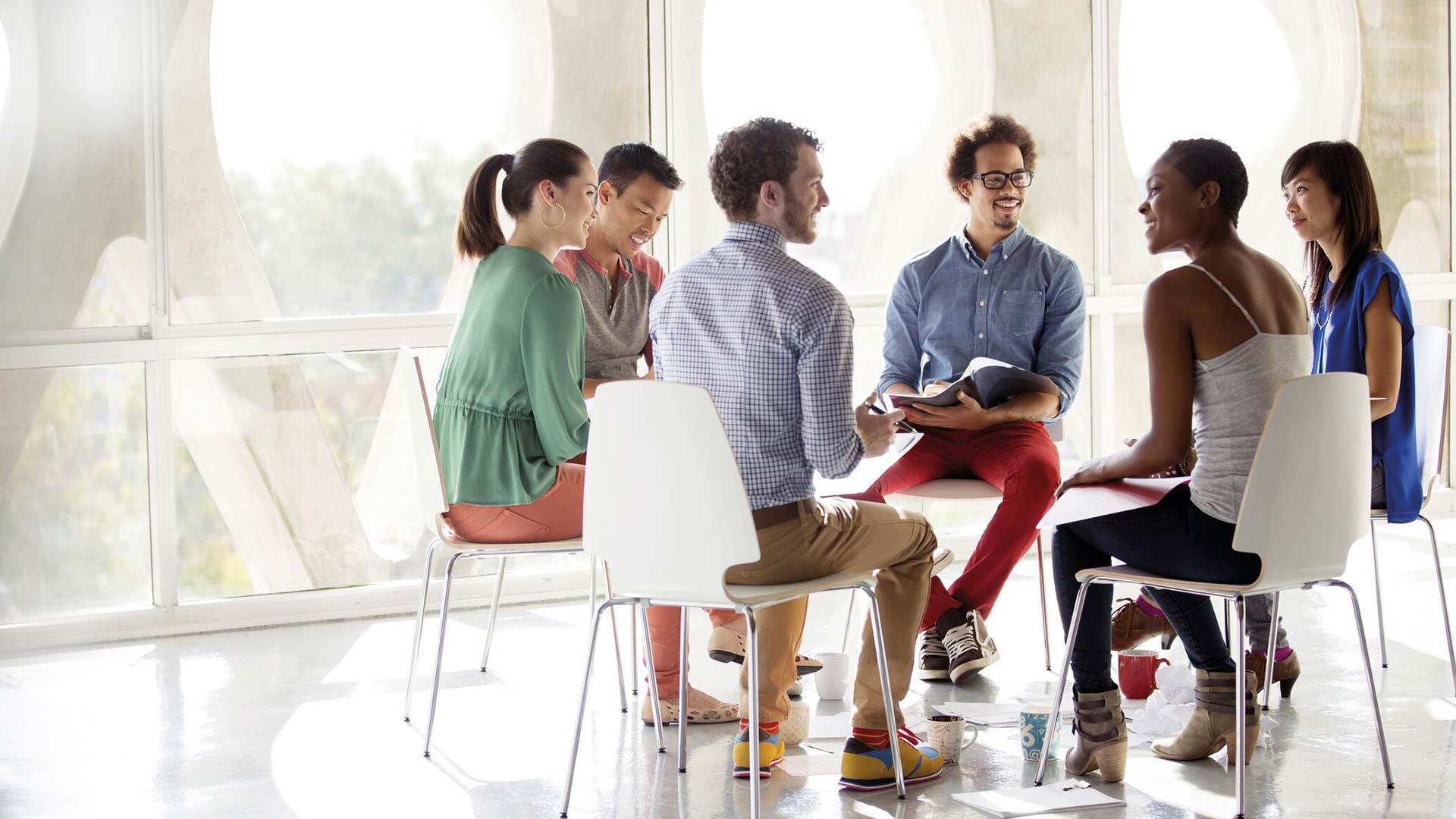 happy men and women sitting in a circle during a business meeting