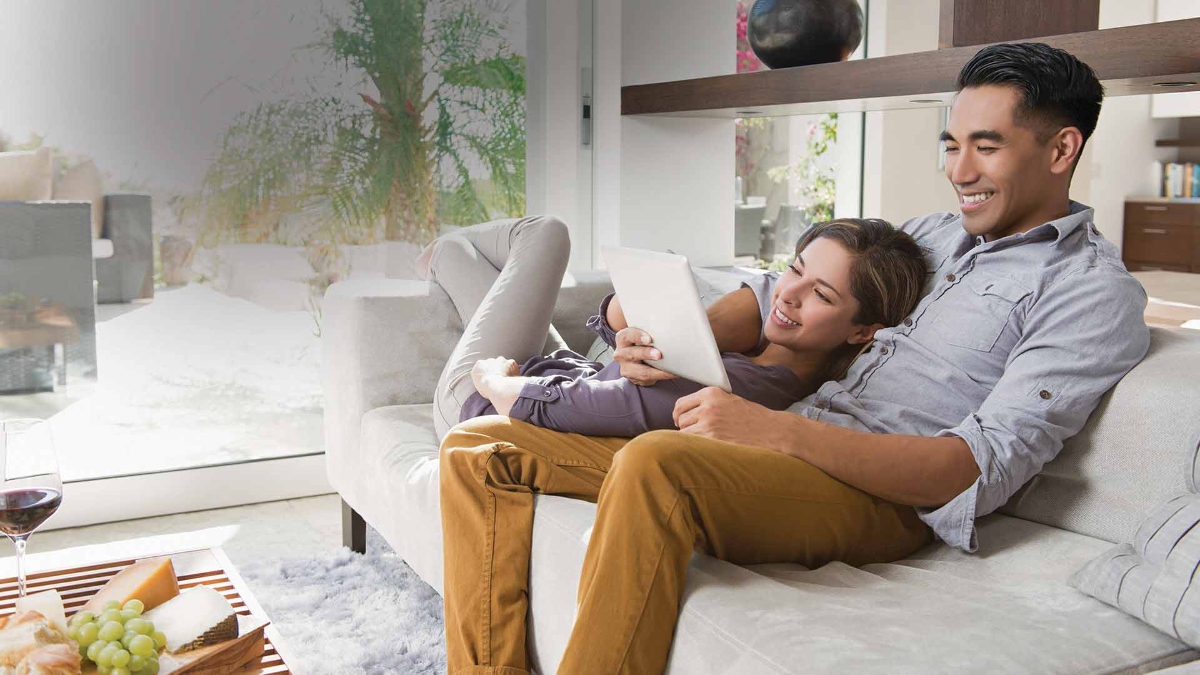 young couple smiling while looking at a digital tablet in smart home