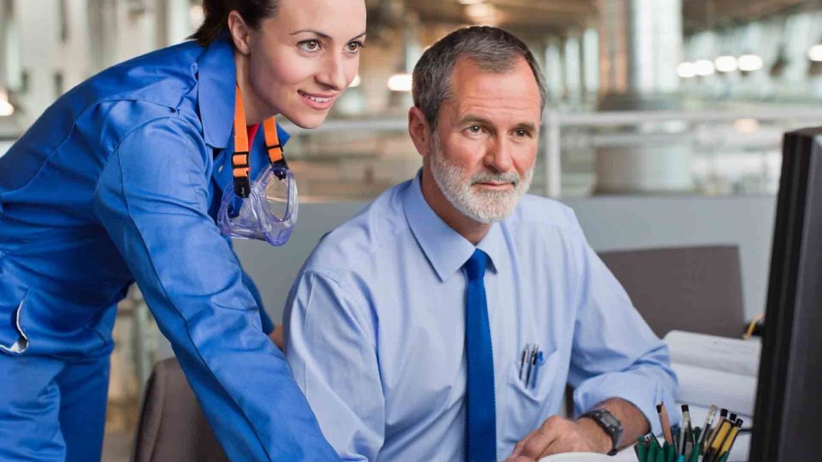 two person talk while looking at laptop
