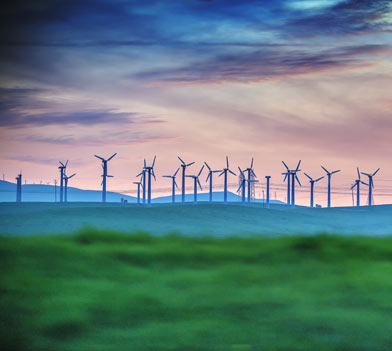 Distant View Of Wind Turbines On Farm At Sunset