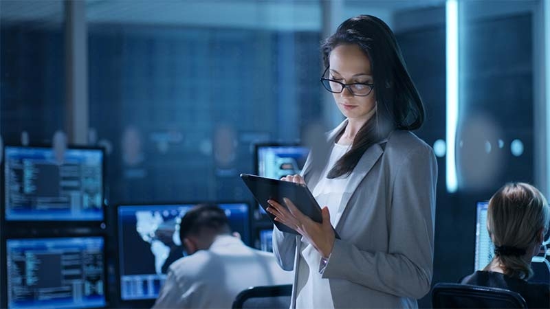 engineer using digital tablet in a data center room to monitor equipment health