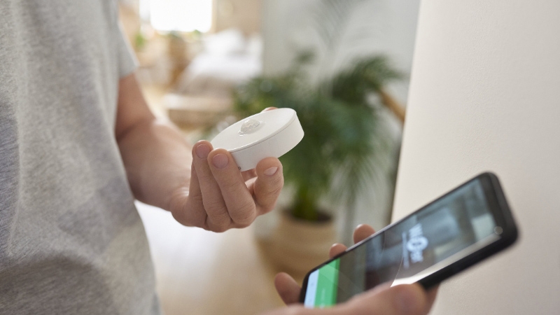 a schneider wifi sensor next to a phone 