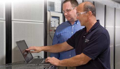 A Schneider Electric employee helping a man with his findings on a machine.