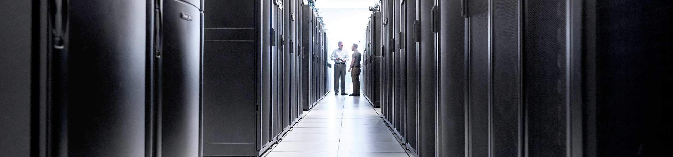 Two men standing in a row of data centers, data center management, IT business.