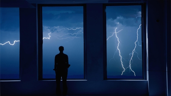 A man looking outside from window at night