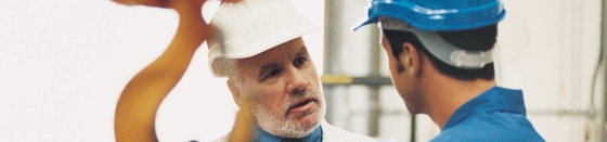 Manager and worker talking on production floor, industrial automation, machine control, hoisting.