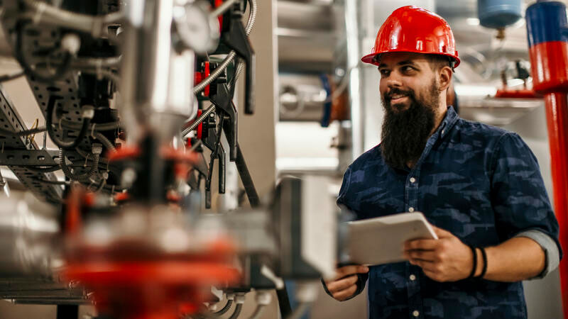 A man is holding a tablet in a factory