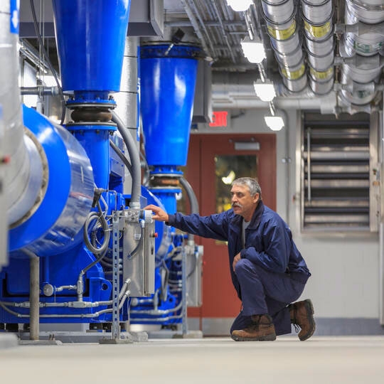 A man is crouching down in the factory