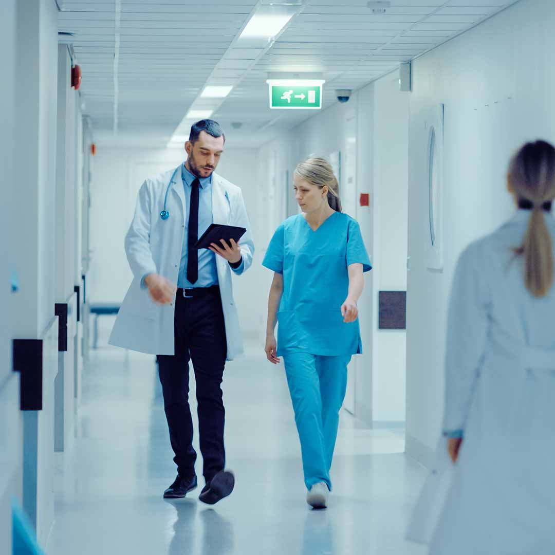 A doctor and a nurse discussing a report while going through the hospital corridor