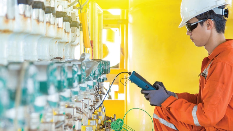 A person in a hard hat and gloves holding a machine