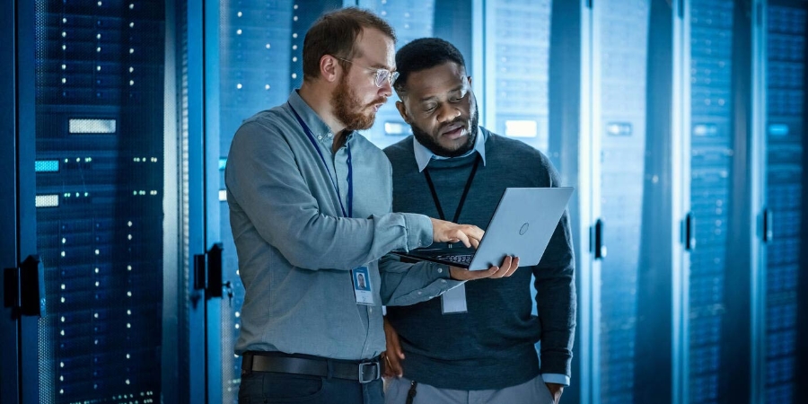 men with laptops discussing in the data center