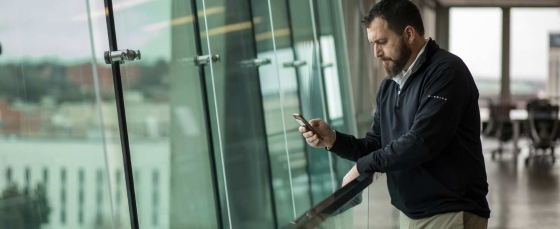 Man looking at smartphone near window of Retirement Systems of Alabama