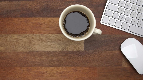 View of a cup of coffee, keyboard, and mouse on the office desk