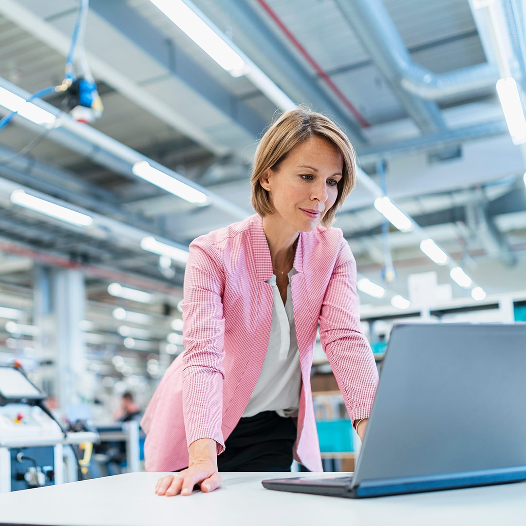 Mature woman working on laptop in a modern factory