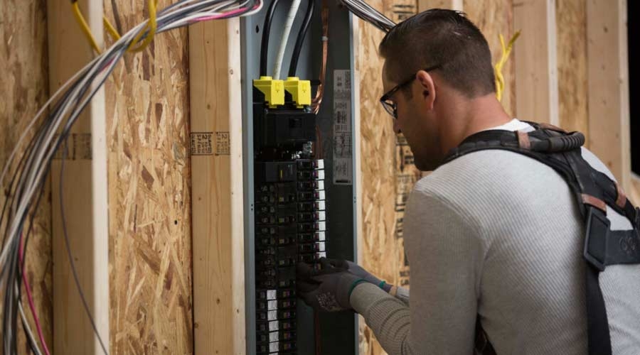 Contractor holding pigtails and circuit breaker in front of Plug-on Neutral load center