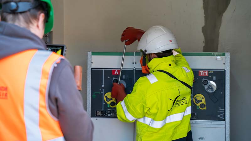 A person wearing a helmet and gloves working on a machine