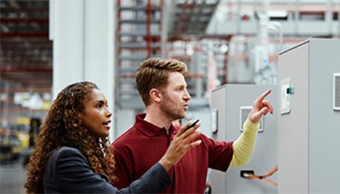 A person and person pointing at a machine