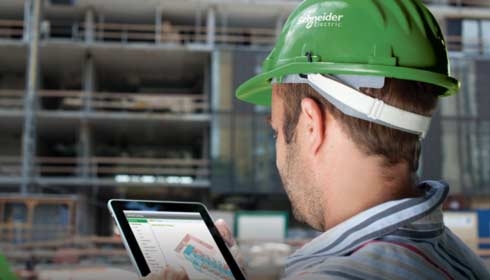Technicus staat met digitaal tablet voor een gebouw in aanbouw