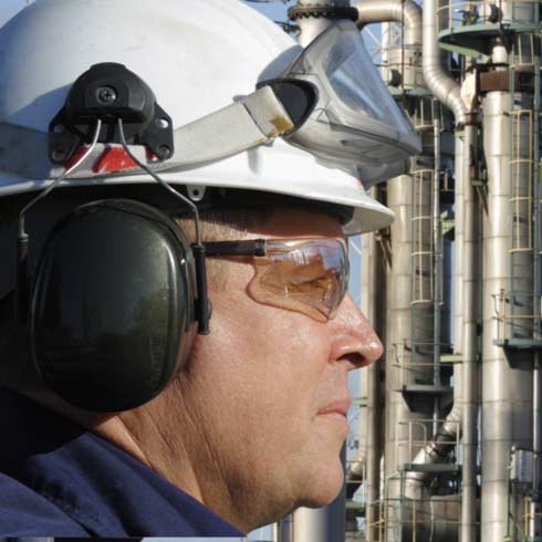 Oliearbeider, engineer, close-up, met grote olieraffinaderij op achtergrond, olie en gas.
