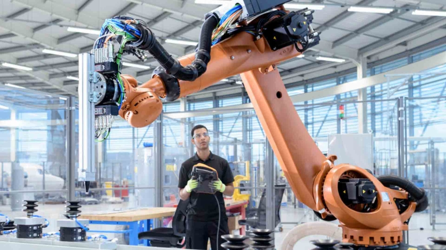 man holding a tablet in front of a robot arm