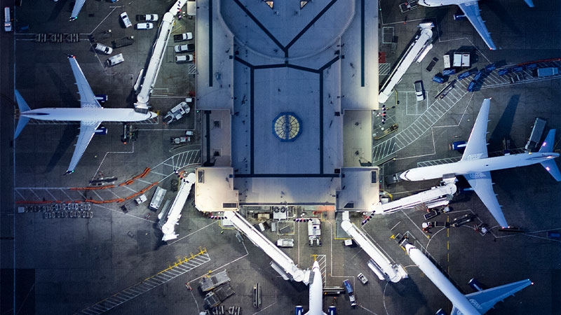 An aerial shot of a fleet of airplanes parked together on the tarmac at the airport.