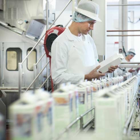 Worker inspecting goats milk in dairy, food and beverage, machine control.