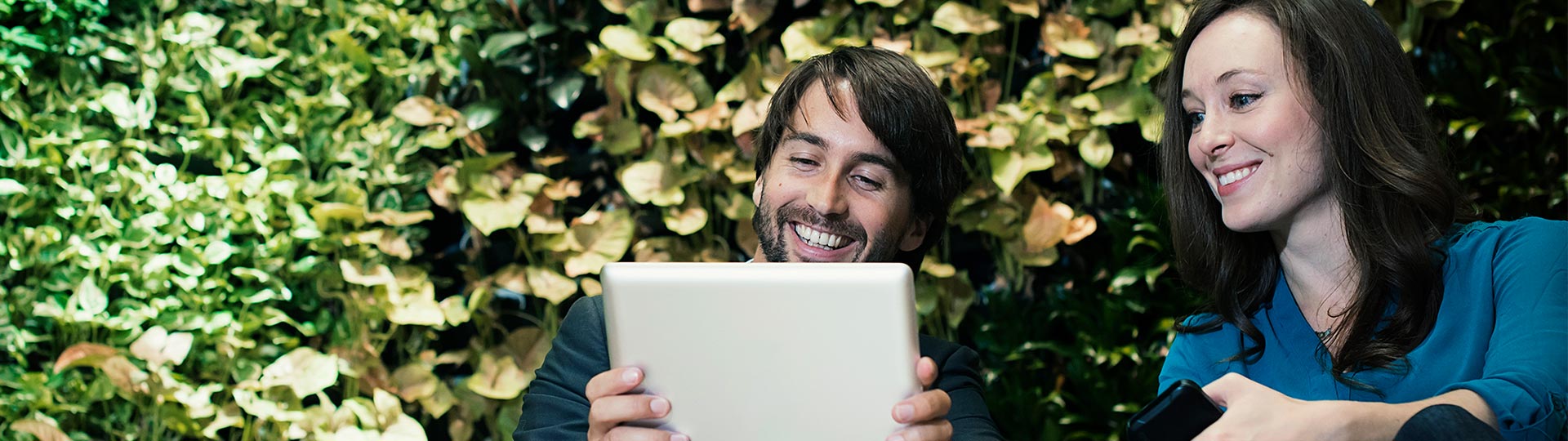 Two People smiling while looking in tablet