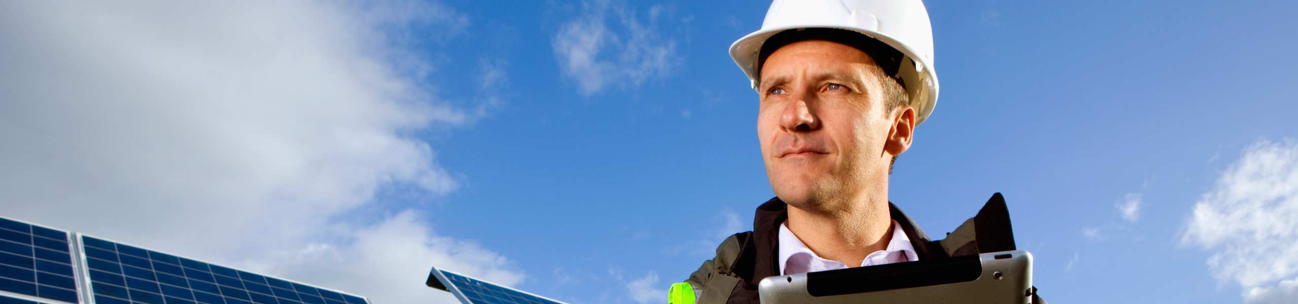 Engineer with digital tablet standing in front of solar panels, energy management.
