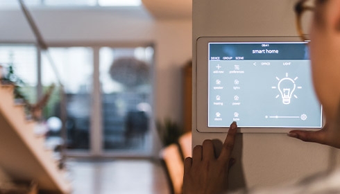A hand pressing a touch screen on a wall