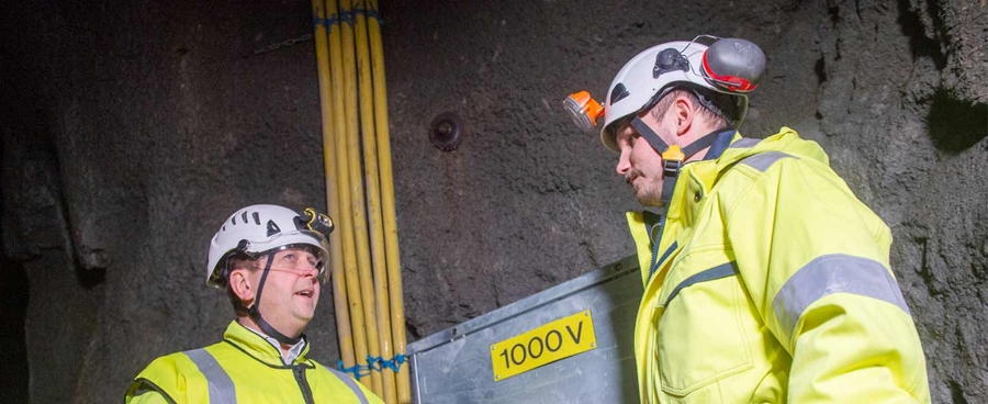 Two men, in the mine, in front of an electrical cabinet