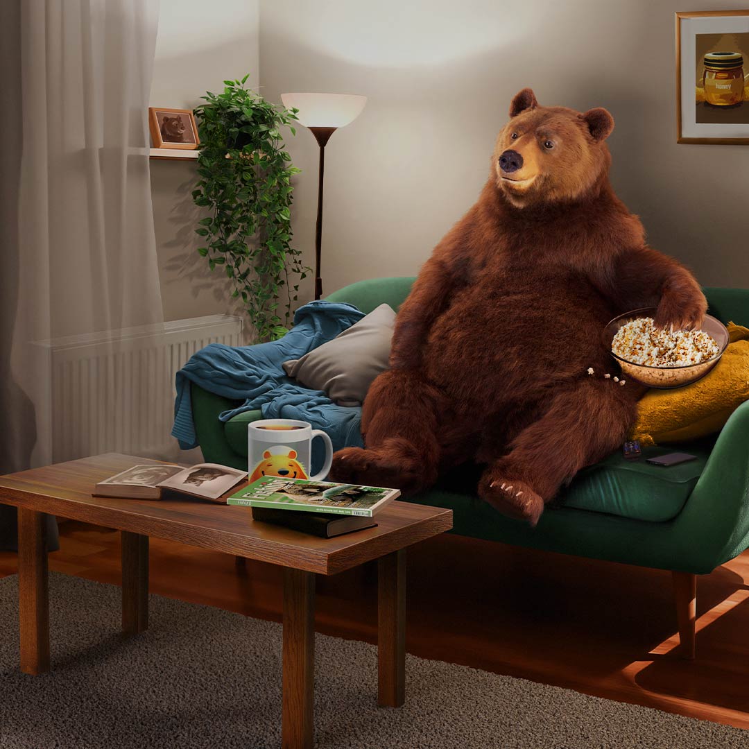 Bear sitting on a couch eating popcorn