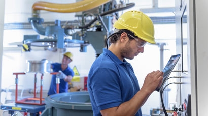 Workers operating environmental testing equipment with digital tablet in electronics factory