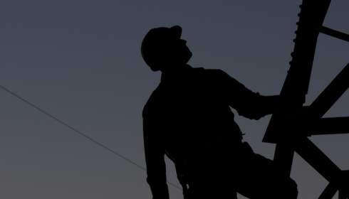 Power utility worker silhouetted, energy access, energy efficiency.