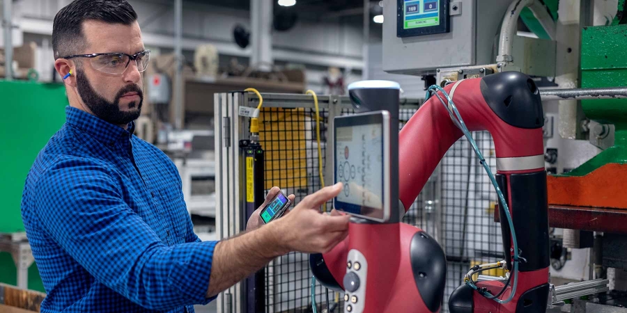 An employee configuring a robotic arm at a factory