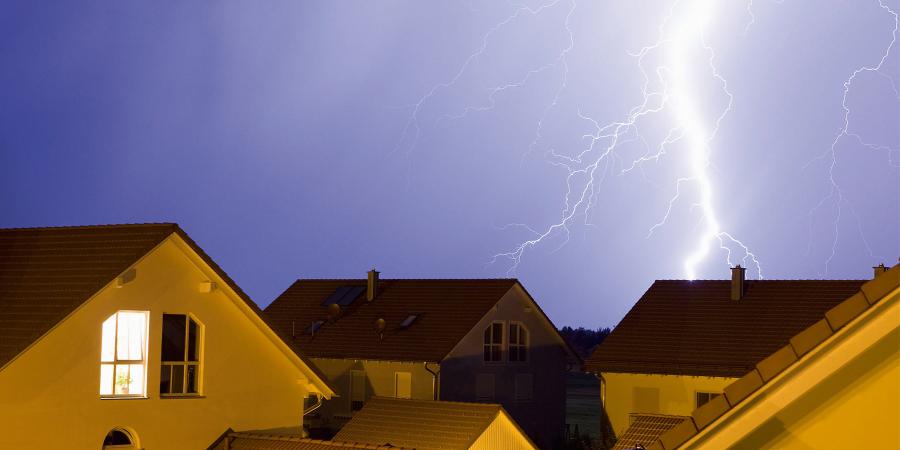 Lightning bolt and thunderhead storms over neighbourhood homes